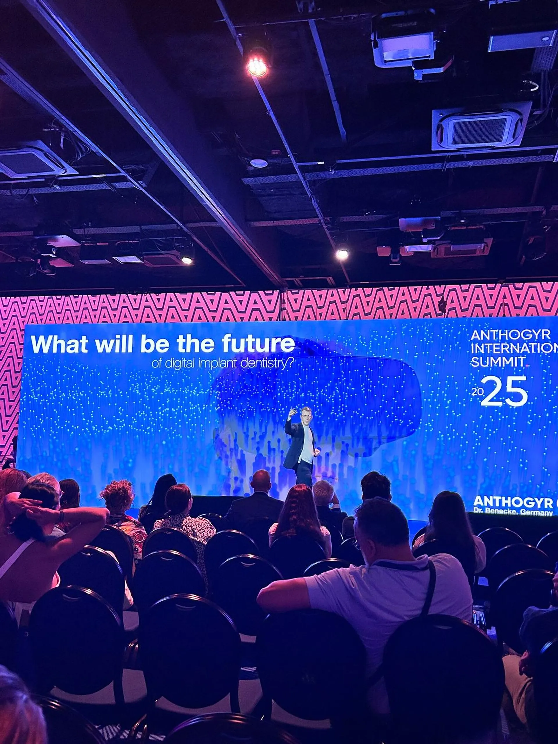 Andreas W. Benecke on stage at the Anthogyr International Summit 2025 in Cannes, in front of the LED wall showing his lecture title